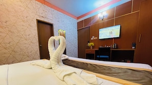 A hotel room with a bed, a TV on the wall, and a wooden cabinet. - Hotel Rosewood Uttara (Dhaka)