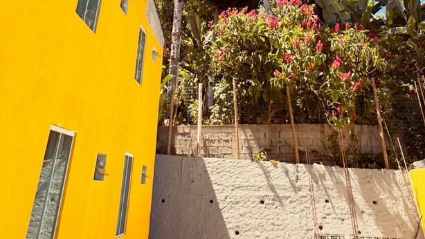 A yellow building with multiple windows and a red roof.