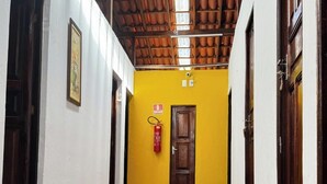 A corridor with a tiled floor, a yellow wall, and a wooden ceiling.