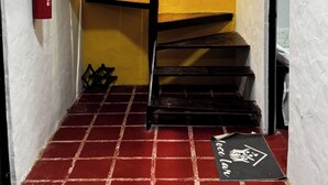 A staircase with a yellow wall and a red-tiled floor leading to a room.