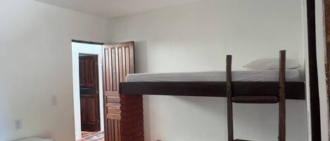 Un dormitorio con literas, un refrigerador pequeño y piso de baldosas.