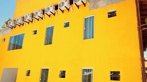 A yellow building with multiple windows and air conditioning units.
