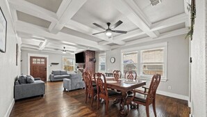 A spacious living room with a dining area, hardwood floors, a ceiling fan, and a fireplace. - Private Fort Worth Getaway Near Botanic Garden! (Fort Worth)