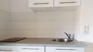 A kitchen with white cabinets, a stainless steel sink, and a countertop.