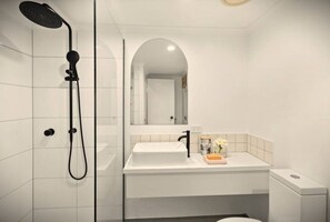A modern bathroom with a white sink, a mirror, and a shower.