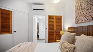 Ein Schlafzimmer mit Bett, Holzschrank und Wand-Klimaanlage.