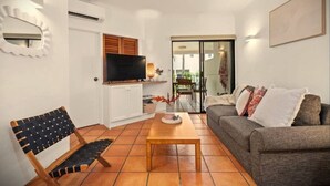Ein Wohnzimmer mit einer Couch, einem Holztisch, einem Fernseher und einem Sessel.
