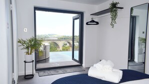 A modern bedroom with a large bed, a view of a bridge, and a potted plant.