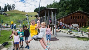A playground with a wooden structure, a rope swing, and a wooden building in the background. - Apartment-Bergblick 80 m2 for up to 6 people (Arnbach)