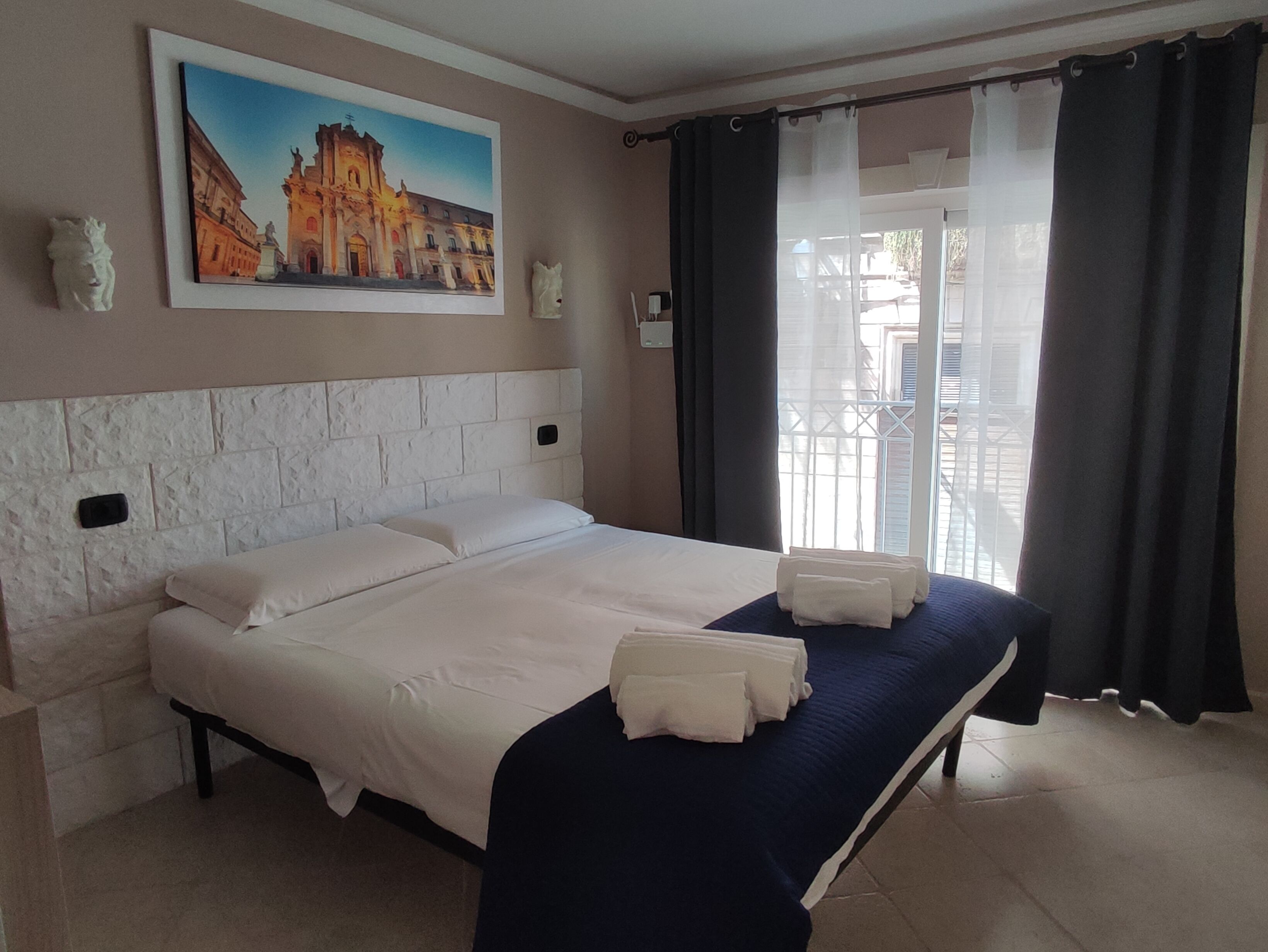 Une chambre d’hôtel avec un grand lit, un tableau au mur et une vue par la fenêtre.