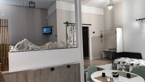Une chambre d’hôtel moderne équipée d’un lit, d’une table à manger, d’un téléviseur et d’un grand miroir.