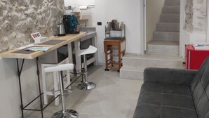 Une cuisine moderne avec un coin bar, une table à manger avec des chaises, un canapé et un escalier menant à un autre niveau.