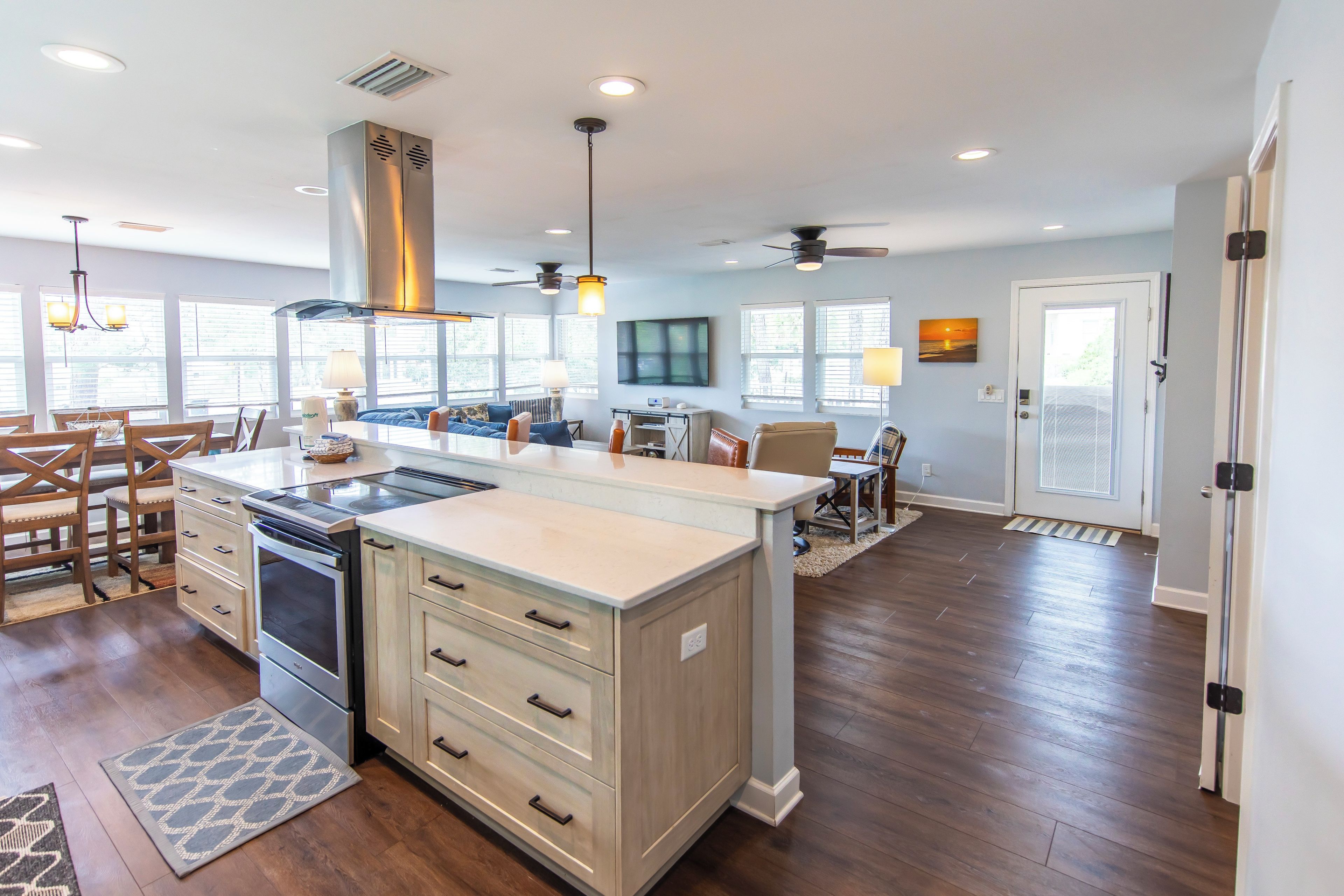 A modern kitchen with a central island, built-in oven, and a dining area with wooden chairs.