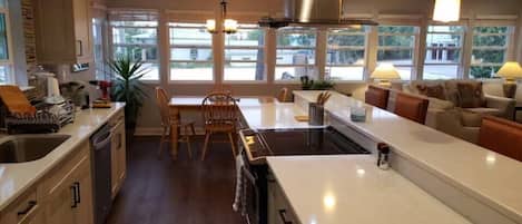 A modern kitchen with a central island, wooden cabinets, and a dining area with a table and chairs.