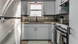 A compact kitchen with a refrigerator, sink, and stove.