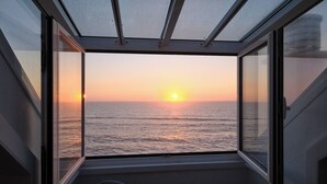 Una stanza con vista sul tramonto sull'oceano, attraverso ampie finestre.