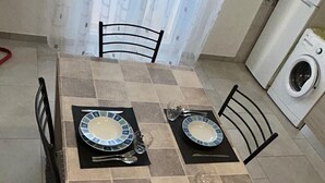 Comedor con mesa empapelada dispuesta para cuatro, con platos, cubiertos y vasos.