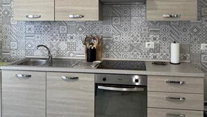 Una cocina moderna con alacenas de madera clara, un lavamanos de acero inoxidable y un horno empotrado.