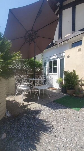Un'area patio con tavolo e sedie, un ombrellone grande e piante in vaso.