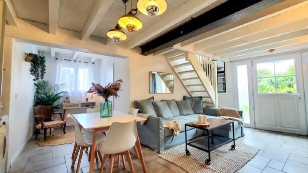 Un vaste espace de vie comprenant une table à manger, des chaises, un canapé et un escalier menant à l’étage supérieur.