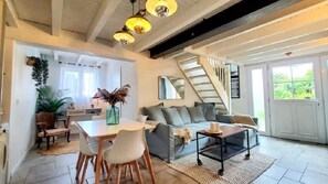 A spacious living area with a dining table, chairs, a sofa, and a staircase leading to an upper level. - COSY HOUSE BEACH AND PORT ON FOOT WITH WIFI (Capbreton)