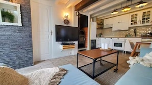 Un salon moderne avec une télévision, une cheminée et un coin cuisine visible à travers une porte ouverte.