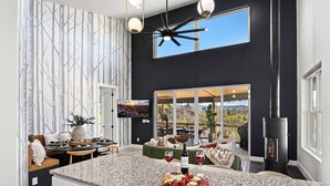 Une cuisine moderne dotée d’un grand îlot central, d’une cuisinière noire et d’un coin repas offrant une vue sur l’extérieur.