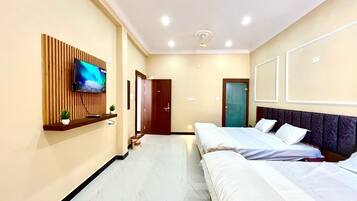 Habitación de hotel con dos camas, un televisor en la pared y una puerta que da a otra habitación.