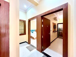 A hallway with wooden doors leading to a bedroom and a bathroom.