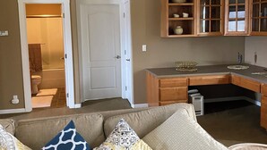A living room with a beige sofa, patterned cushions, and wooden cabinets in the background.
