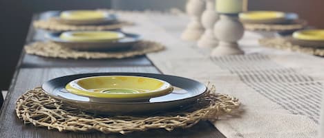 A wooden table set with plates, candles, and a woven placemat.