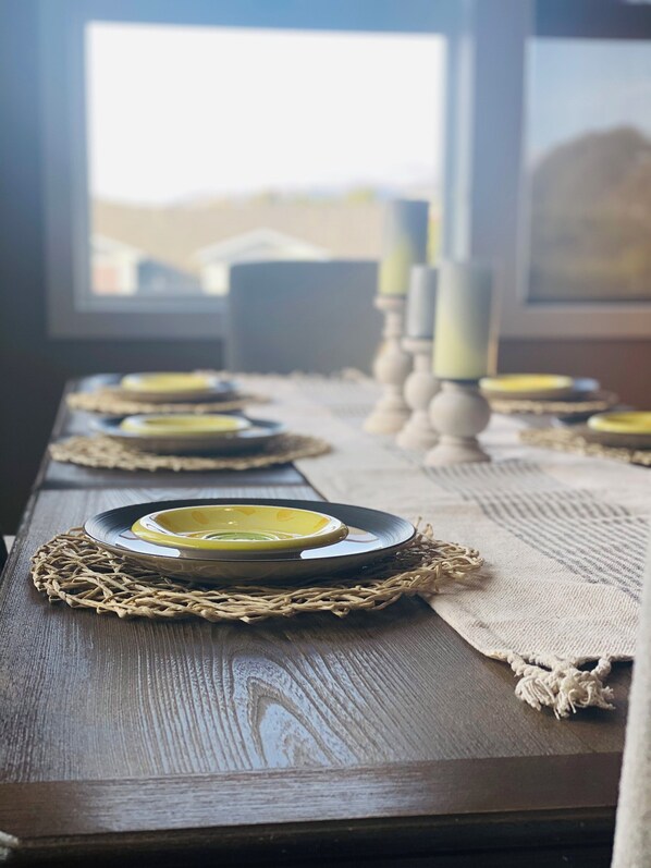 Una mesa de madera dispuesta con platos, velas y un mantel tejido.