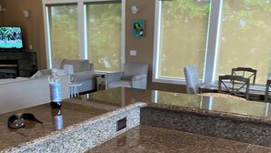 A kitchen with granite countertops, wooden cabinets, and a dining area with a table and chairs.