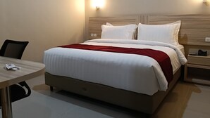 A hotel room with a bed, a desk, and two wall-mounted lights. - Sunflower Hotel Syariah Near Juanda (Sidoarjo)