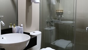 A modern bathroom with a glass-enclosed shower, a white sink, and a toilet. - Sunflower Hotel Syariah Near Juanda (Sidoarjo)