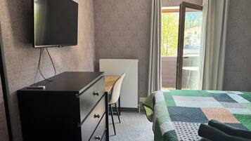 A hotel room with a bed, a desk, a chair, a television, and a window with curtains.