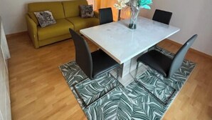 Ein Essbereich mit einem weißen Tisch, schwarzen Stühlen und einem Teppich mit Muster.