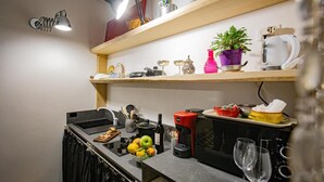 Een kleine keuken met een spoelbak, aanrecht en een koffieapparaat.