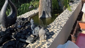 Jardí de roques amb una estàtua de Buda, una gran roca central i una petita bassa.