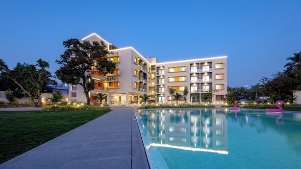 A modern hotel with a swimming pool, multiple balconies, and well-lit outdoor areas. - Saavi Suites (Daman)
