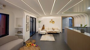 A modern living room with a sofa, a coffee table, and a decorative rug. - Saavi Suites (Daman)
