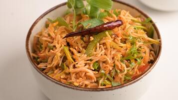 A bowl of food with a red chili and green garnish on top.