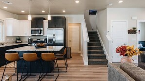 A modern kitchen with a central island, stainless steel appliances, and a staircase leading to a living area.