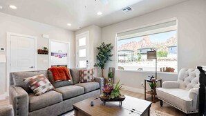 A living room with a grey sofa, a wooden coffee table, a white armchair, and a piano.