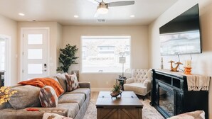A living room with a sofa, coffee table, fireplace, and a television mounted on the wall.