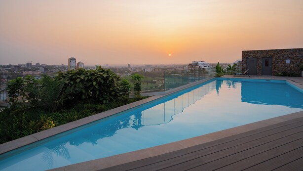 Une piscine avec vue sur la ville au coucher du soleil.