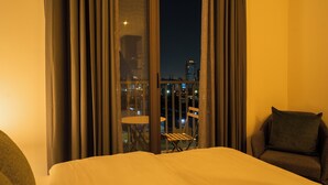 Une chambre d’hôtel avec un lit, une chaise et un balcon équipé d’une table et de chaises.
