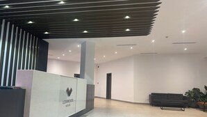 Un espace d’accueil moderne comprenant un comptoir de réception portant l’inscription « LOXWOOD HOUSE », un canapé de couleur foncée et une plante en pot.