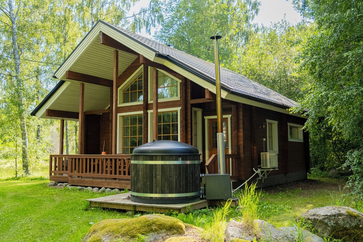 A wooden cabin with a large outdoor grill, surrounded by lush greenery.