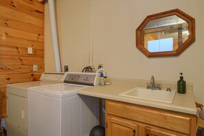 Un área de lavandería con lavadora, secadora, lavabo y espejo.